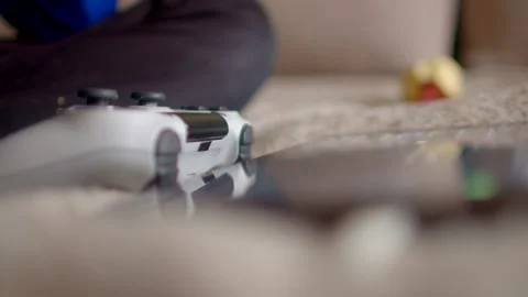 In the living room, a game controller is on the couch, with a mobile device visi Stock Footage 295932061