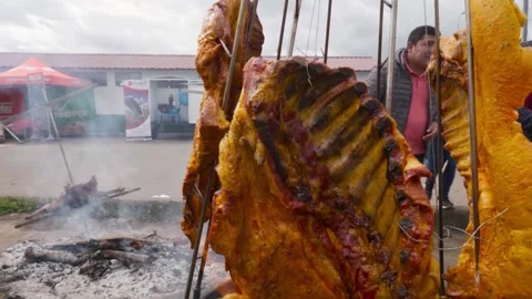 Llanera style beef ribs roasting over fire at outdoor food festival Video stock 335700734