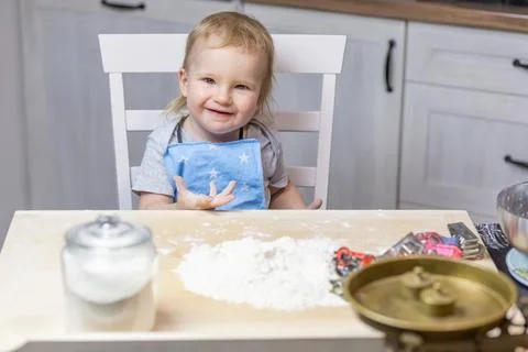 Llittle cute boy is posing at the table in the kitchen. Stock Photos