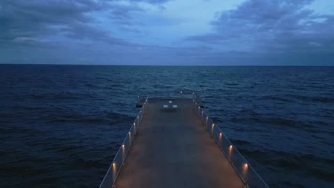 Lluminated pier with dramatic sky over stormy dark sea at evening Stock-Footage 255674755