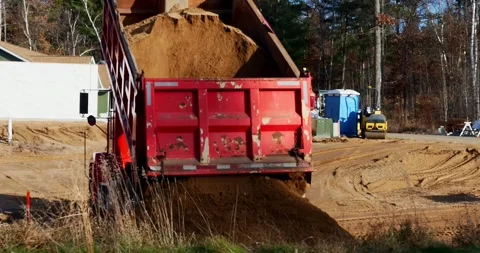 Load of dirt is emptied from the box of a red dump truck into a pile. Vídeos de archivo 322720584