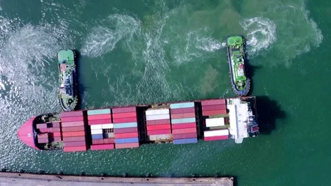 Loaded container cargo vessel traveling being assisted by tugboat docking on Stock Footage 336446216