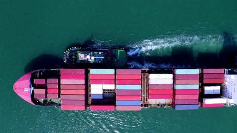 Loaded container cargo vessel traveling being assisted by tugboat docking on Stock Footage 336446392