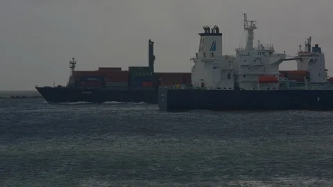 A loaded container ship appearing from behind another then travelling out to sea Vídeos de archivo 115502548