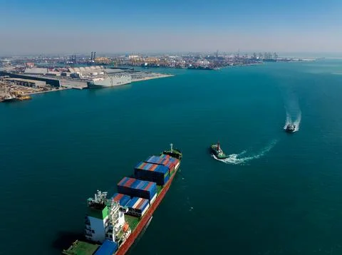 Loaded Container Ship Navigating Ocean Waters With Tugboats At Industrial H.. Фото