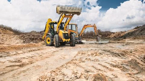 A loader and mini excavator are working in a construction quarry. Earthen e.. Photos