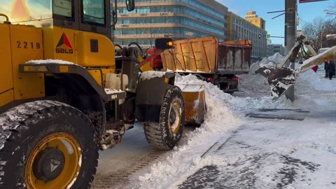 A loader collects snow from the road for loading into a dump truck. TheSnow.. Stock Footage 328069662