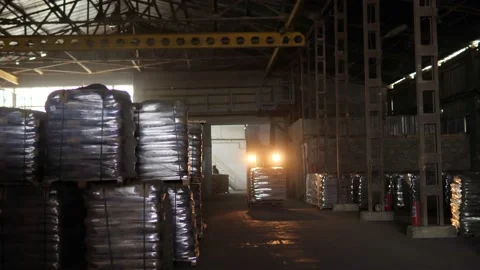 The loader driver loads and unloads pallets with bags in a very dark warehouse Video stock 156382988