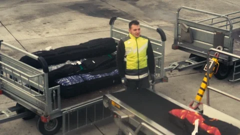 A loader loads the baggage of passengers on the carrier. Unloading baggage Video stock 123918442