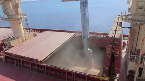 A loader loads a cargo ship's hold through a pipe Stock Footage 147732880