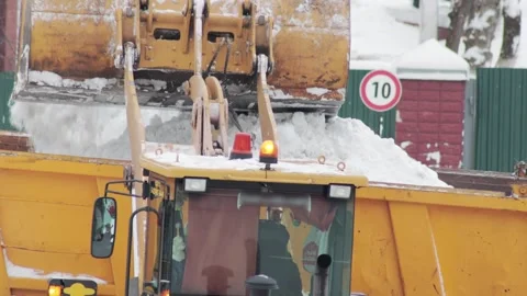 A loader loads snow into a truck to remove snow from city streets in winter Stock Footage 255636711
