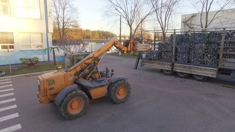 The loader loads the trailer with bales of compressed plastic. Aerial view. 4K Stock Footage 76463631