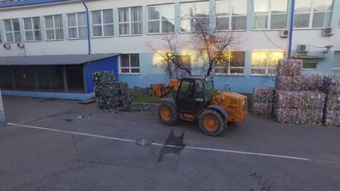 The loader loads the trailer with bales of compressed plastic. Aerial view. 4K Stock Footage 76472217