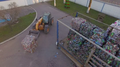 The loader loads the trailer with bales of compressed plastic. Aerial view. 4K Stock Footage 76491436