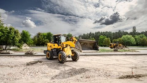 A loader moves dirt while a bulldozer prepares the area at the landscape site Stock Photos