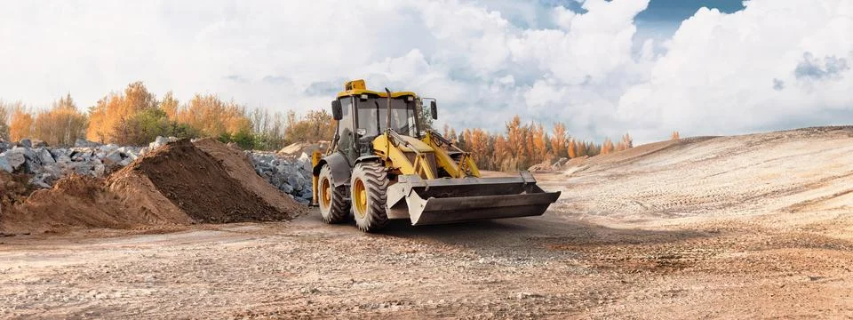 A loader operates on a construction site, moving dirt while surrounded by pil Stockfoto's