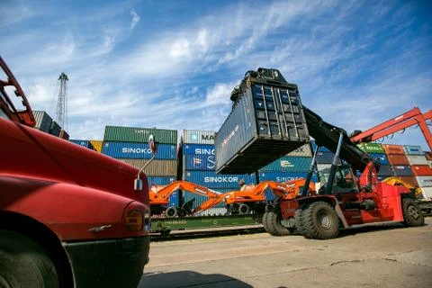 Loader passing by warehouses with containers. Stock Photos