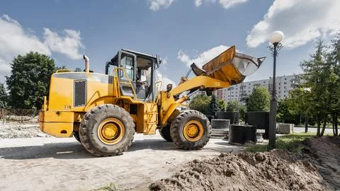 A loader is positioned on a construction site in a city. The operator control Stock Photos
