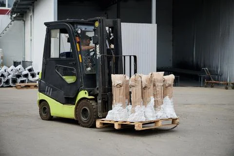 A loader transports pipes to a container ship in the yard of the plant near the Stock Photos