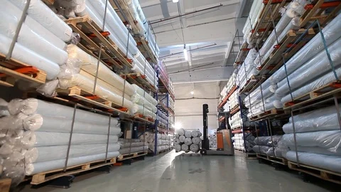 The loader unloads shelves with material rolls, storage of fabrics in the Stock Footage 91537284