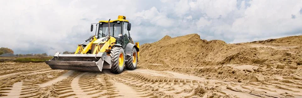 A loader uses its bucket to grade a construction site. Space for text Stock Photos