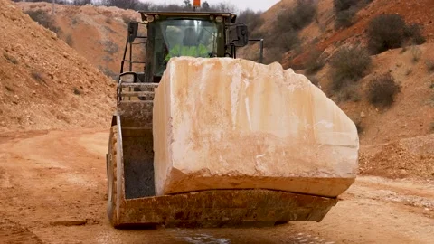 Loader vehicle with driver CAT 966M carrying huge limestone block at Stock Footage 236888632