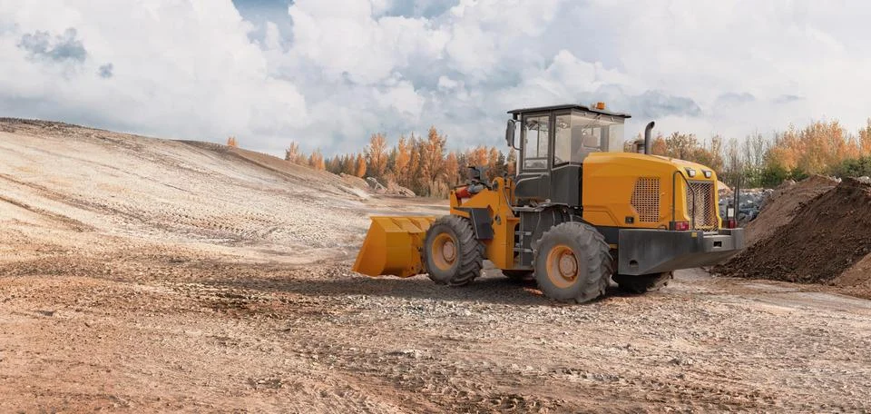 A loader is working on a construction site to level the ground. The sky is cl Photos