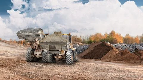 Loader works at construction site moving dirt and materials to a pile. The eq Photos