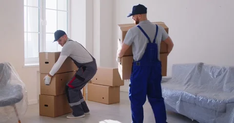 Loaders are seen working diligently as they transport cardboard boxes into Video stock 311228179