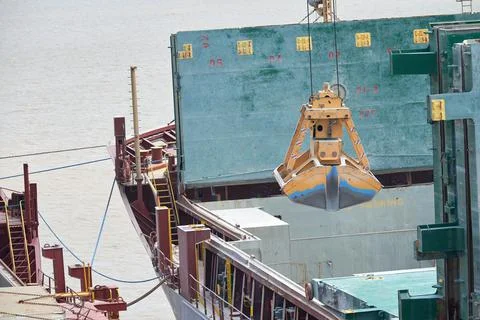 Loading and dischargind operation of bulk cargo bauxite on bulk carrier ship  Stock Photos