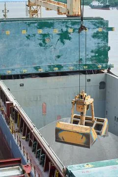 Loading and dischargind operation of bulk cargo bauxite on bulk carrier ship  Stock Photos