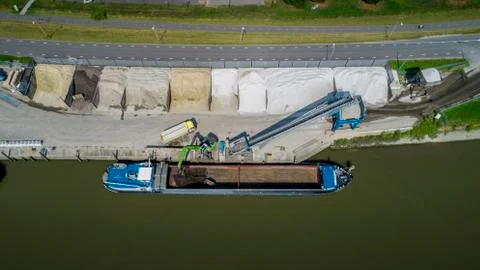Loading barge with sand and rubble on a small berth. Freight transport Stock Photos