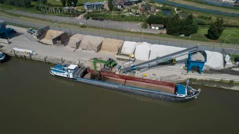 Loading barge with sand and rubble on a small berth. Freight transport Stock Photos