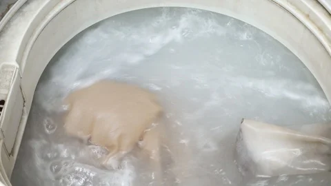 Loading of bed linen and clothes in the washing machine. The water for washin Stock Footage 86270510