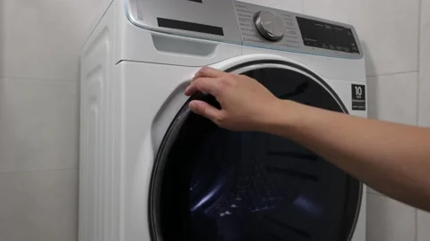 Loading Clothes Into the Drying Machine. Putting Clothes Into the Drying Machine Stock Footage 202077517