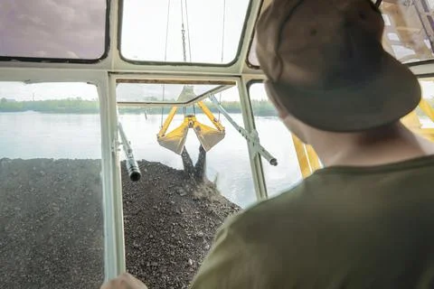 Loading coal onto a barge ship on a floating crane, view from the crane operator Stock Photos