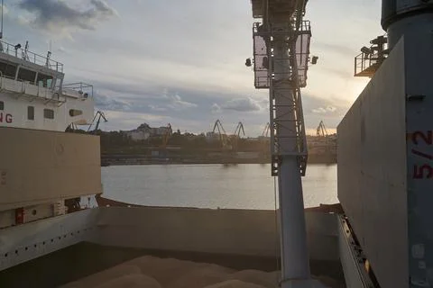 Loading corn onto a bulk carrier ship in the port at the grain terminal. Port Stock Photos
