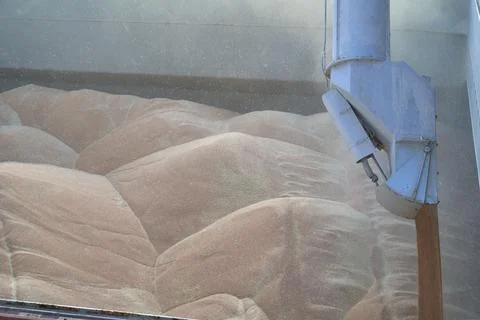 Loading corn onto a bulk carrier ship in the port at the grain terminal. Port Stock Photos
