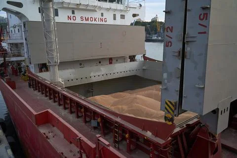 Loading corn onto a bulk carrier ship in the port at the grain terminal. Port Stock Photos