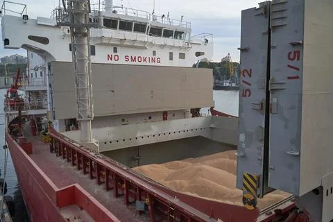 Loading corn onto a bulk carrier ship in the port at the grain terminal. Port Stock Photos