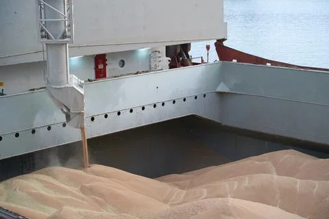Loading corn onto a bulk carrier ship in the port at the grain terminal. Port Stock Photos