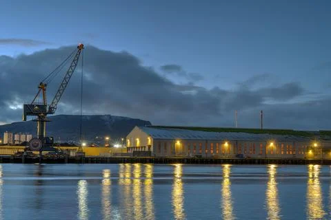 A loading crane and a storehouse at dusk Stock Photos