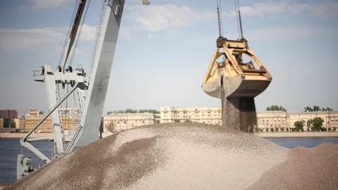 The loading crane discharges crushed stone from the barge to the pier. Stockbeeldmateriaal 78770668