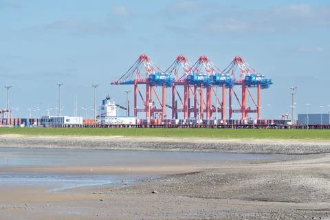 Loading cranes in an industrial cargo port surrounded by Wadden Sea Stock Photos