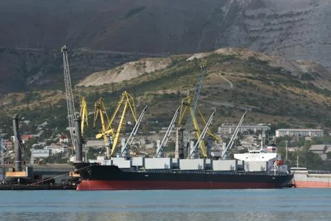 Loading cranes at the seaport unload or load a cargo ship. Cargo ship for bul Stock Photos