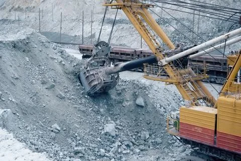 Loading of crushed stone into trolleys using an excavator. Stock Photos