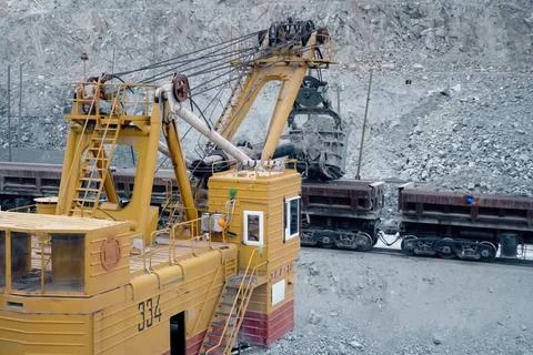 Loading of crushed stone into trolleys using an excavator. Stock Photos