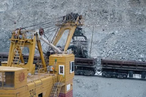 Loading of crushed stone into trolleys using an excavator. Stock Photos