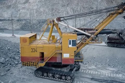 Loading of crushed stone into trolleys using an excavator. Stock Photos