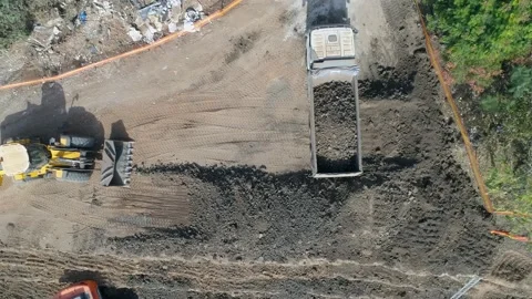Loading dirt, debris and junk on truck container. Aerial shot above excavator Stock Footage 131016535